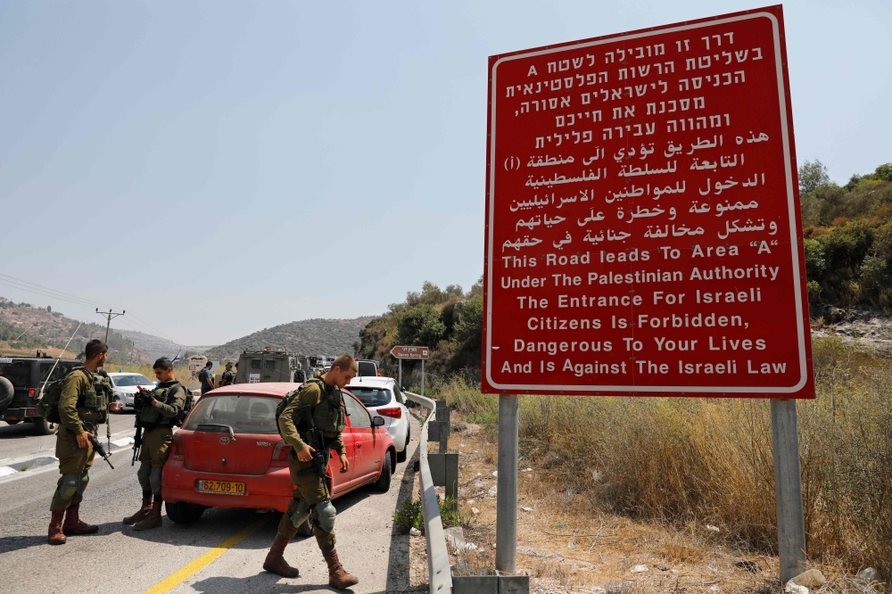 Israeli security forces gather at the site where a bomb exploded near the Israeli settlement of Dolev in the occupied West Bank on Friday. — AFP