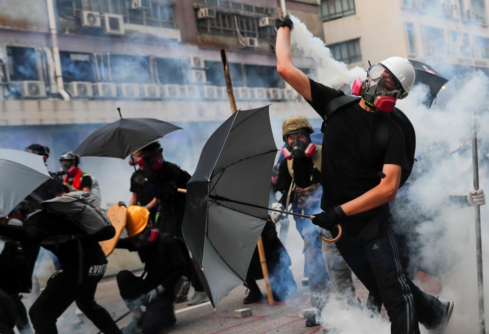 A demonstrator throws back a tear gas canister as they clash with riot police during a protest in Hong Kong on Saturday. -Reuters