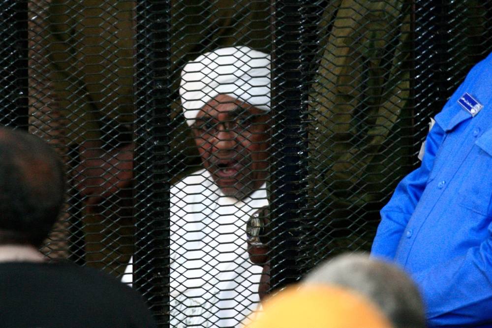 Sudan's deposed military ruler Omar Al-Bashir sits in a defendant's cage during his corruption trial in Khartoum on Saturday. -AFP