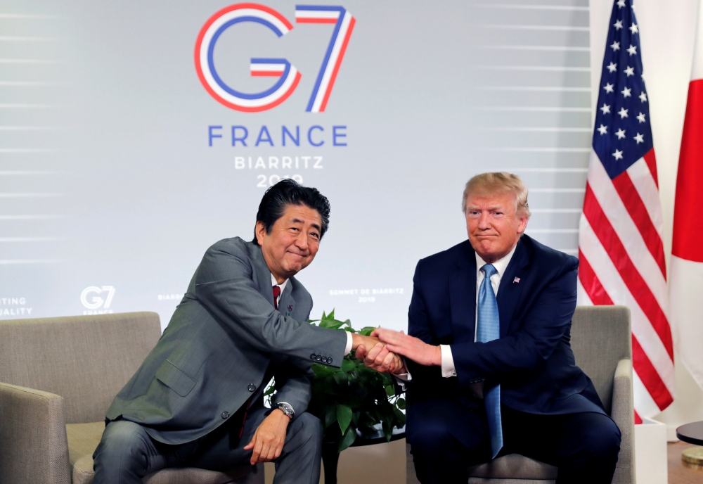 US President Donald Trump and Japan's Prime Minister Shinzo Abe shake hands as they attend a bilateral meeting during the G7 summit in Biarritz, France, on Sunday. -Reuters