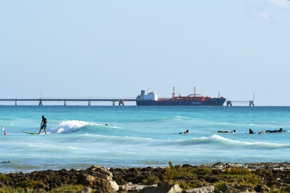 A man surfs as a ship sails next to the 