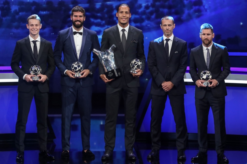 (FromL) Dutch midfielder Frenkie de Jong, Brazilian goalkeeper Alisson Becker, Dutch defender Virgil van Dijk, UEFA President Aleksander Ceferin and Argentinian forward Lionel Messi pose with their trophy at the end of the UEFA Champions League football group stage draw ceremony in Monaco on Thursday. — AFP