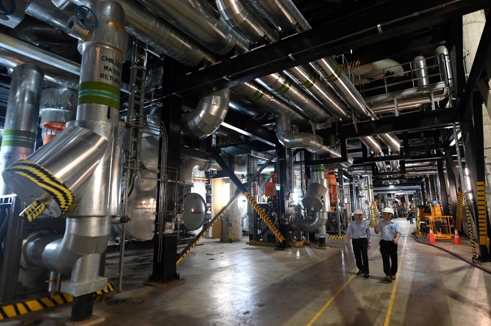 This photograph taken on August 21, 2019 shows two men walking in the underground cooling system installation of the Marina Bay Sands hotel and resort in Singapore. -AFP