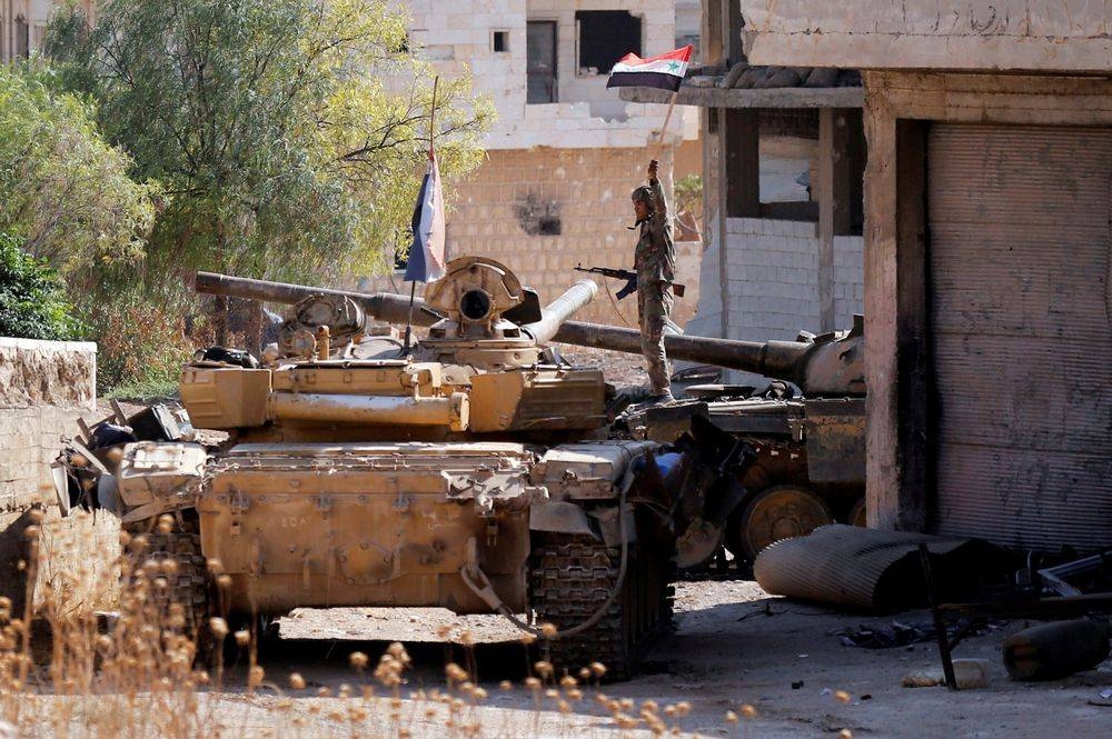 A Syrian army soldier holds a Syrian flag as he stands on a military vehicle in Khan Sheikhoun, Idlib. — Reuters 