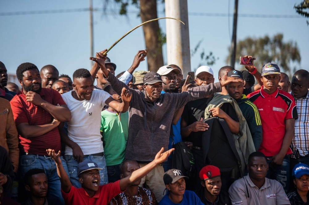 Zulu residents of the Jeppe Men Hostel scream waving batons in the Johannesburg CBD on Tuesday after South Africa's financial capital was hit by a new wave of anti-foreigner violence. -AFP