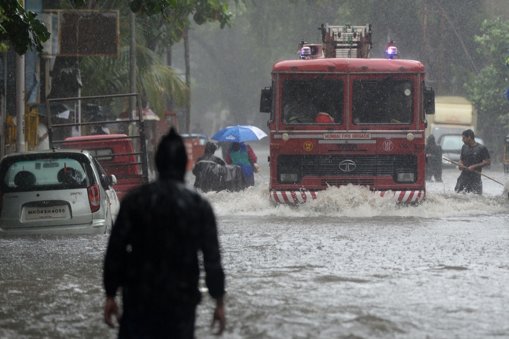 A fire engine drives through a flooded road during heavy rain showers in Mumbai on Wednesday. — AFP