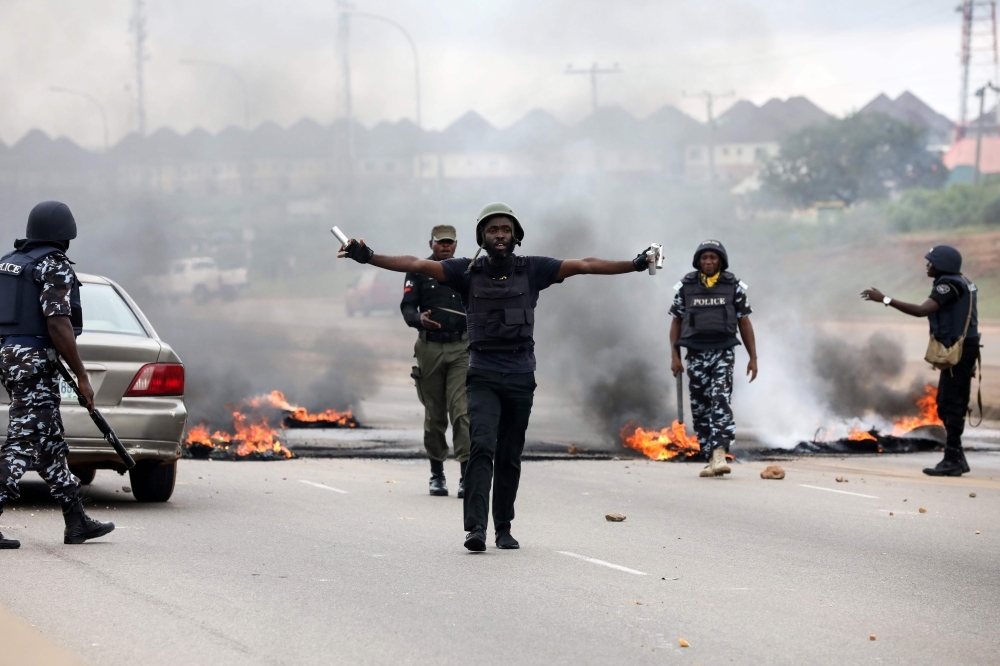 Anti-riots policemen try to calm down protestors during a demonstration and attacks against South Africa's owned shops in Abuja, Nigeria, on Wednesday. — AFP