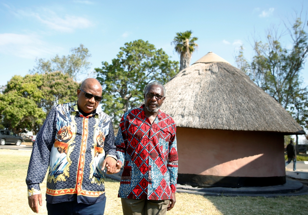 Former Zimbabwe President Robert Mugabe's nephews Leo Mugabe and Philip Chiyangwa hold hands as they walk at their uncle's rural homestead in Kutama, Zimbabwe, on Saturday. — Reuters