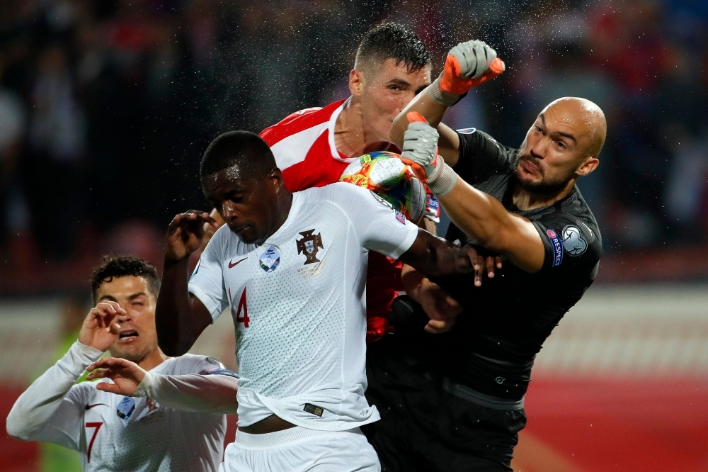 Portugal's William Carvalho (2ndL) vies with Serbia's goalkeeper Marko Dmitrovic (R) during the Euro 2020 football qualification match between Serbia and Portugal in Belgrade, on Saturday. — AFP