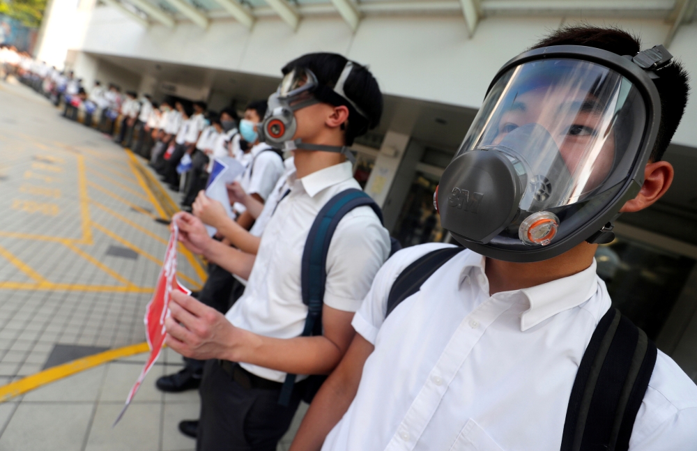 Secondary school students wearing masks join a human chain protesting against what they say is police brutality against protesters, after clashes at Wan Chai district in Hong Kong, on Monday. -Reuters