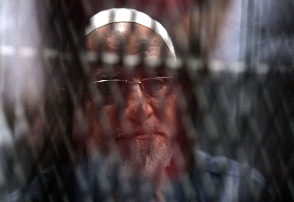 Egyptian Muslim Brotherhood Supreme Guide Mohamed Badie is seen behind bars during a verdict and sentencing session of a retrial for him and other Brotherhood members on charges of espionage with the Palestinian Hamas group at the Tora courthouse complex in southeastern Cairo on Wednesday. — AFP