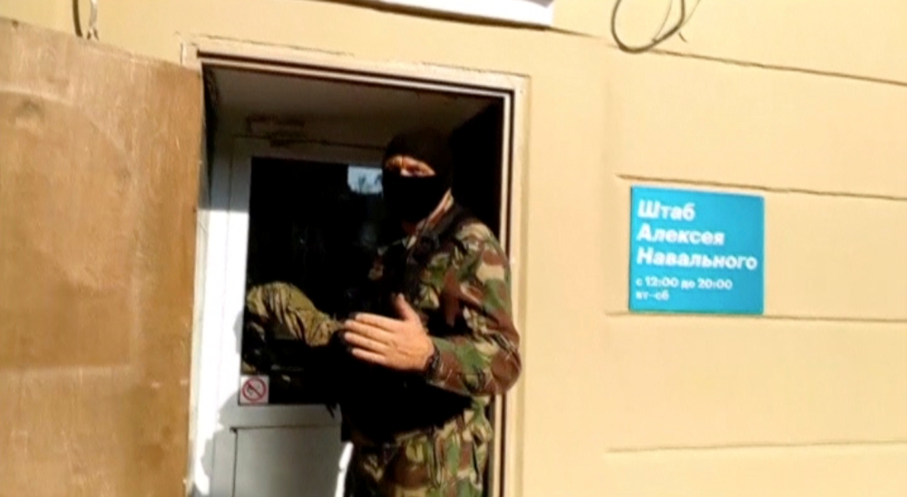 A still image taken from a video footage shows a masked law enforcement officer addressing journalists during a raid in a local office of Kremlin critic Alexei Navalny in Perm, Russia, on Thursday. — Reuters