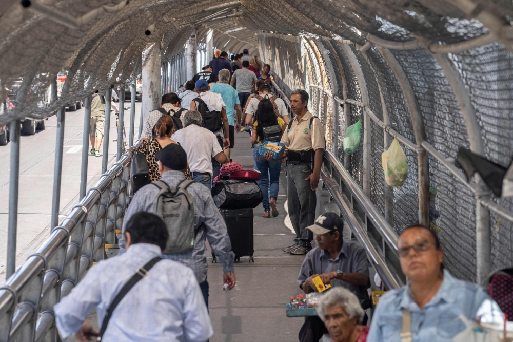 A man sells candy as pedestrian commuters make their way across the Paso del Norte Bridge at the Mexico-US border in Ciudad Juarez, Mexico, on Thursday. — AFP