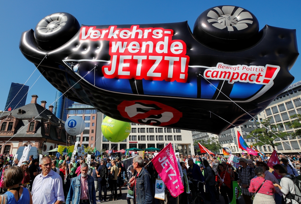 People stand under an inflatable car with a sign reading 