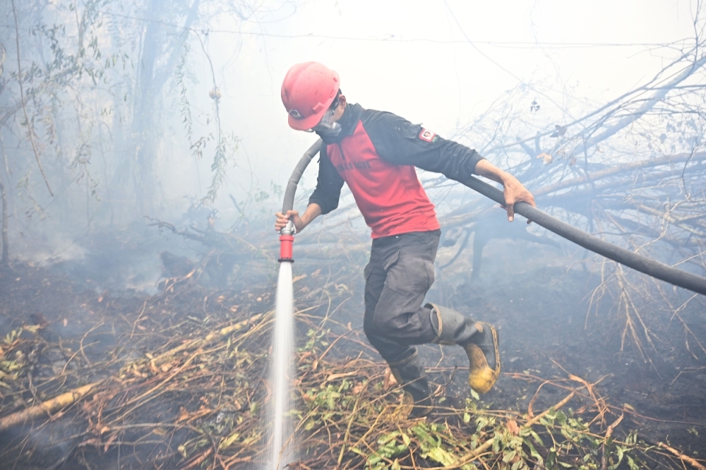 An Indonesian firefighter extinguishes a fire in Kampar on Monday. -AFP  