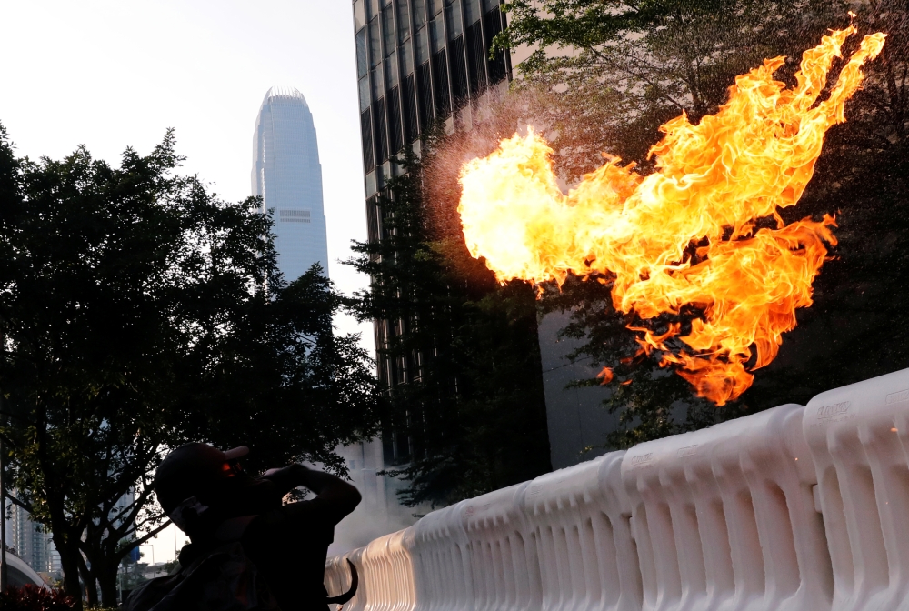 An anti-government protester throws a Molotov cocktail during a demonstration near Central Government Complex in Hong Kong on Sunday. -Reuters