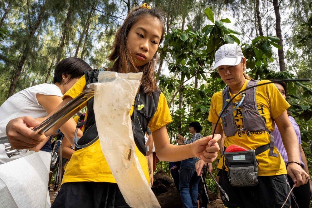 In this picture taken on August 25, 2019, 12-year-old Ralyn Satidtanasarn, known by her nickname Lilly, collects plastic waste during the Trash Hero cleaning initiative at the Khung Bang Kachao urban forest and beach in Bangkok. -AFP