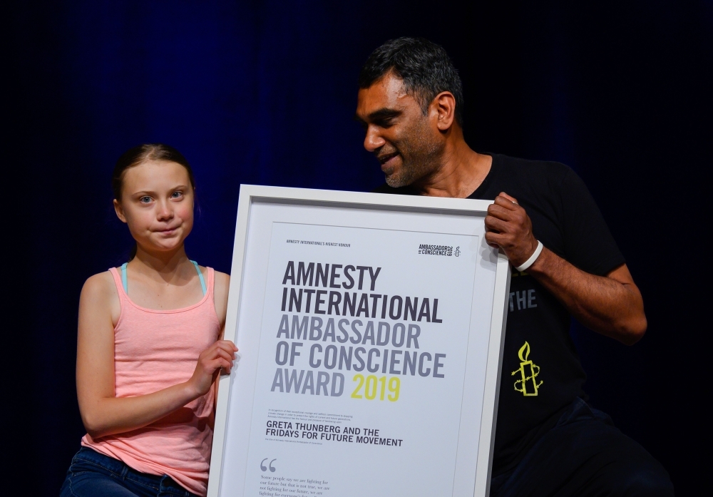 Swedish climate activist Greta Thunberg poses with Amnesty International Secretary General Kumi Naidoo after she received Amnesty International's Ambassador of Conscience award at George Washington University in Washington, DC on Monday. -AFP