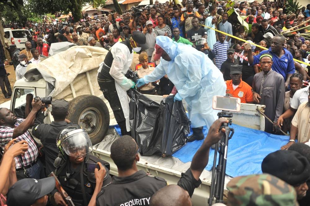 Rescuers hold a body after a fire at a school killed dozens of children and two teachers in Monrovia, Liberia, on Wednesday. — AFP