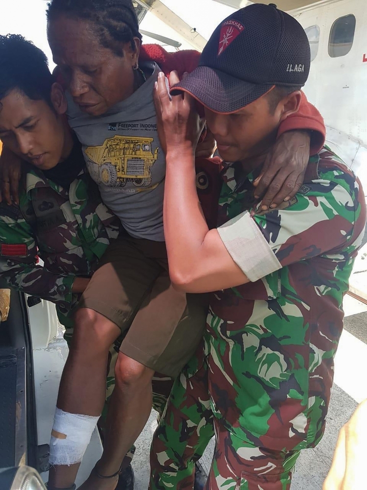 This handout picture by the Indonesian National Armed Forces (TNI) shows Indonesian soldiers carrying a man with a gunshot wound in Ilaga, Papua.  A toddler and teenager were among three people killed in a gunfight between security forces and independence-seeking rebels in Indonesia's restive Papua region, the military said on Tuesday. — AFP