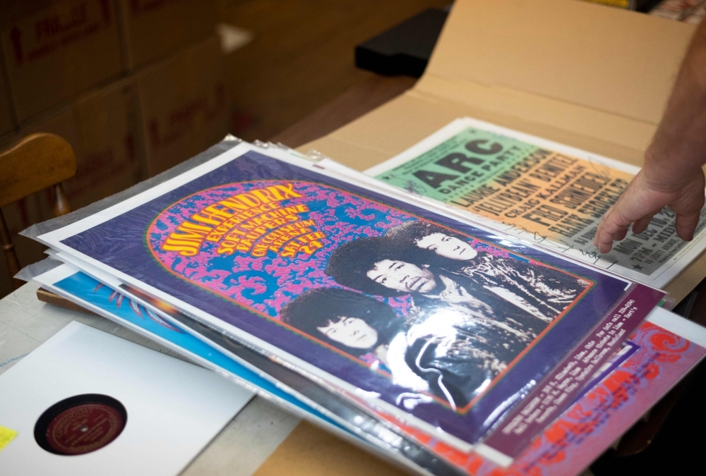 In this file photo Bob George, the Co-Founder and Director of the ARChive of Contemporary Music, points to a poster of the Jimi Hendrix Experience  in New York City. The turntable needle drops and the reverbs of the obscure band The Motifs ring out, bouncing off mountains of records lining the musty warehouse housing America's largest pop music collection.The cavernous independent private music library, known as the ARChive of Contemporary Music, on a non-descript street in lower Manhattan's Tribeca neighborhood claims more than three million recordings — mostly vinyl and some CDS and cassettes, not to mention a vast collection of memorabilia.  — AFP