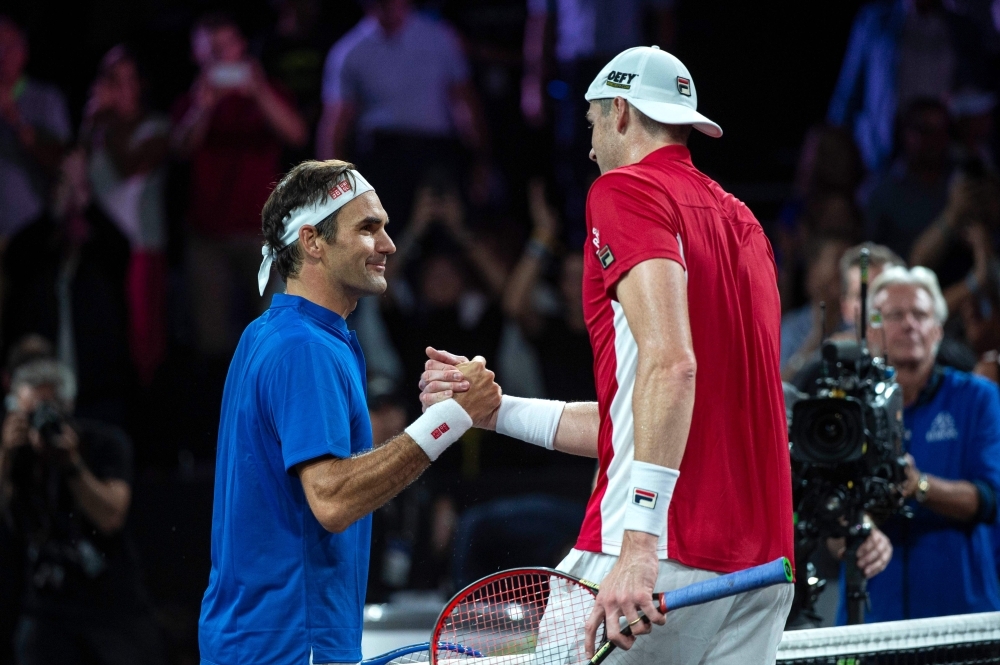 Team Europe's player Roger Federer (L) shakes hands with Team World's player John Isner (R) after winning his match during the 2019 Laver Cup tennis tournament in Geneva, on September 22, 2019. — AFP