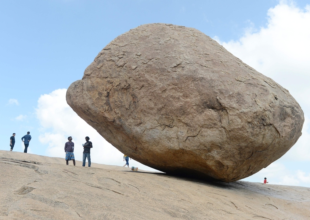 Visitors stand beside the granite boulder 'Krishna's Butterball' at Mahabalipuram on Thursda. The world heritage site of Mahabalipuram could be one of the ports of call for Chinese President Xi Jinping when he holds a summit with his Indian counterpart Narendra Modi reported by Indian media to be held from Oct. 11-13 in the southern state of Tamil Nadu state. — AFP