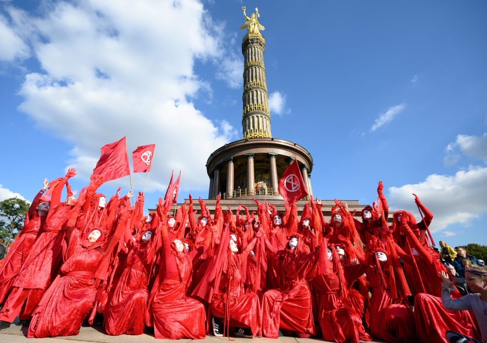 Supporters of the Extinction Rebellion socio-political movement fighting against climate breakdown, biodiversity loss and the risk of ecological collapse wear red costumes as they perform during a road block in Berlin on Monday. — AFP