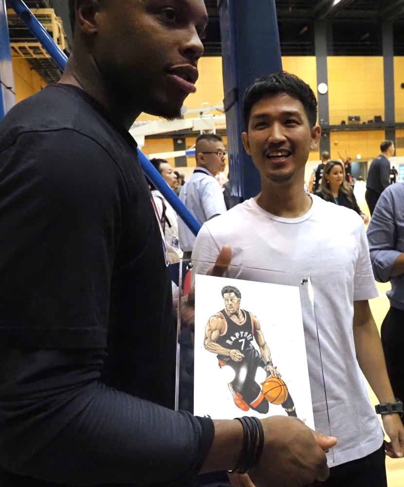 Toronto Raptors guard Kyle Lowry (L) receives an illustration from a Japanese fan (R) prior to a training session by the NBA basketball team in Tokyo, on Monday. The Raptors are in Tokyo to play exhibition matches this week. — AFP