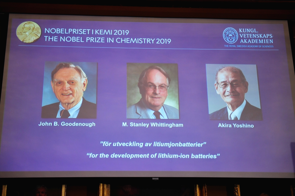 A screen displays the portraits of the laureates of the 2019 Nobel Prize in Chemistry John B. Goodenough, left, M. Stanley Whittingham, center, and Akira Yoshino 