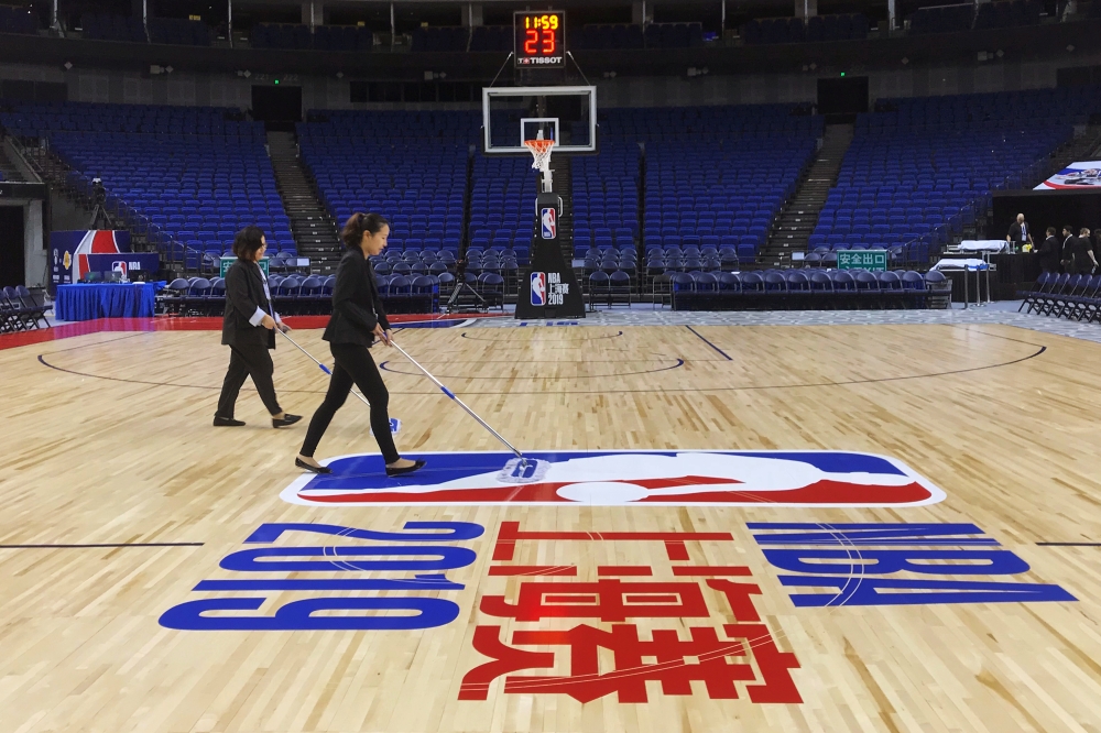 Staff members clean court floor before the NBA exhibition game between Brooklyn Nets and Los Angeles Lakers at the Mercedes-Benz Arena in Shanghai, China, on Thursday. — Reuters