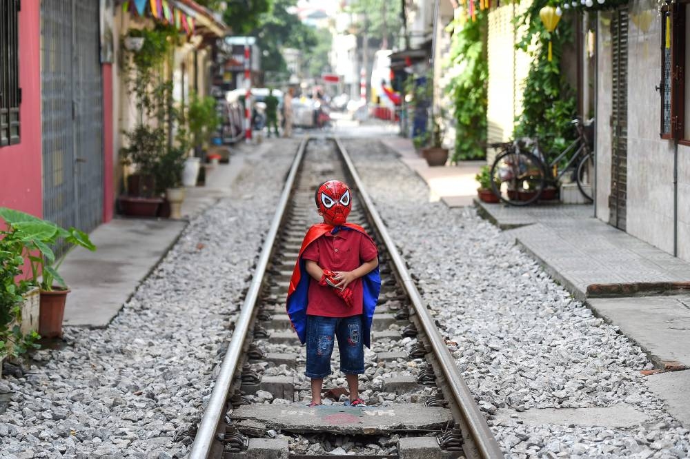 A boy wearing a Spiderman costume stands on Hanoi's popular train street on October 10, 2019 following a municipal authorities order to deal with cafes and 