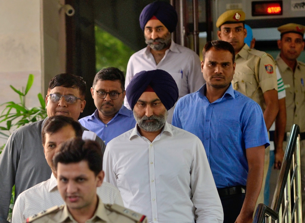 Police escort Malvinder Singh and his brother Shivinder Singh, former directors of Ranbaxy Laboratories, inside a court premises in New Delhi, India, on Friday. — Reuters