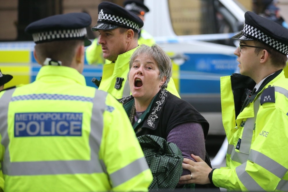 An activist from the Extinction Rebellion climate action movement is detained by police after she locked herself on to the entrance of the building housing the government's Department for Transport in central London on Tuesday. — AFP