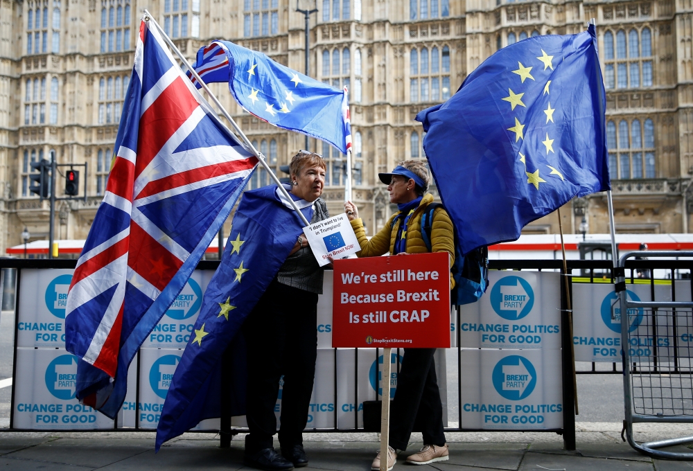 Anti-Brexit protesters hold flags outside the Houses of Parliament in London on Tuesday. — Reuters