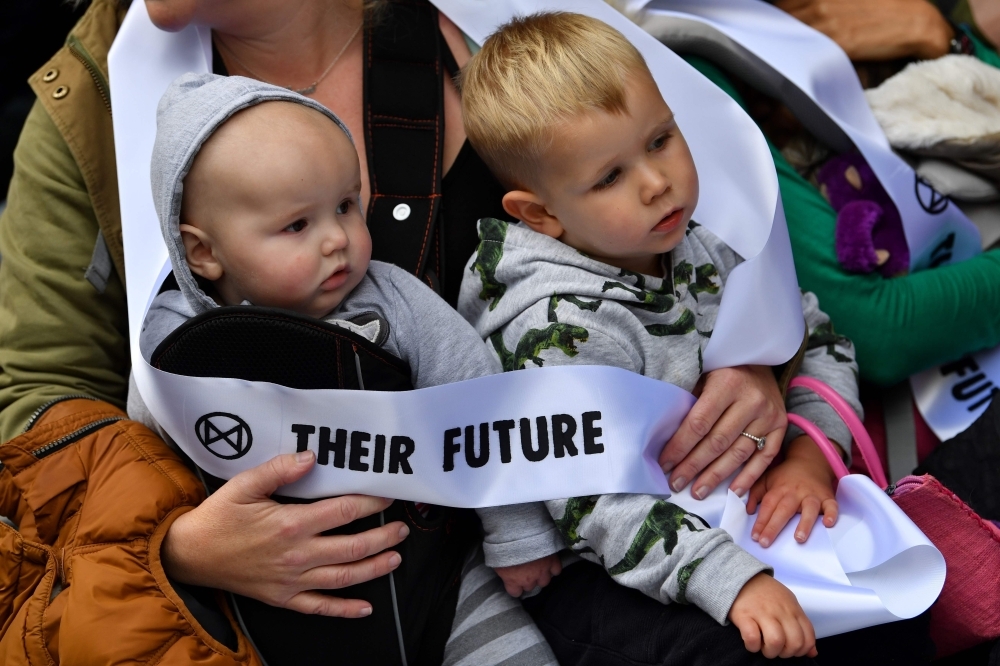 Mothers hold their babies as they protest about the climate crisis outside Google offices during the tenth day of demonstrations by the climate change action group Extinction Rebellion, in London, on Wednesday. — AFP