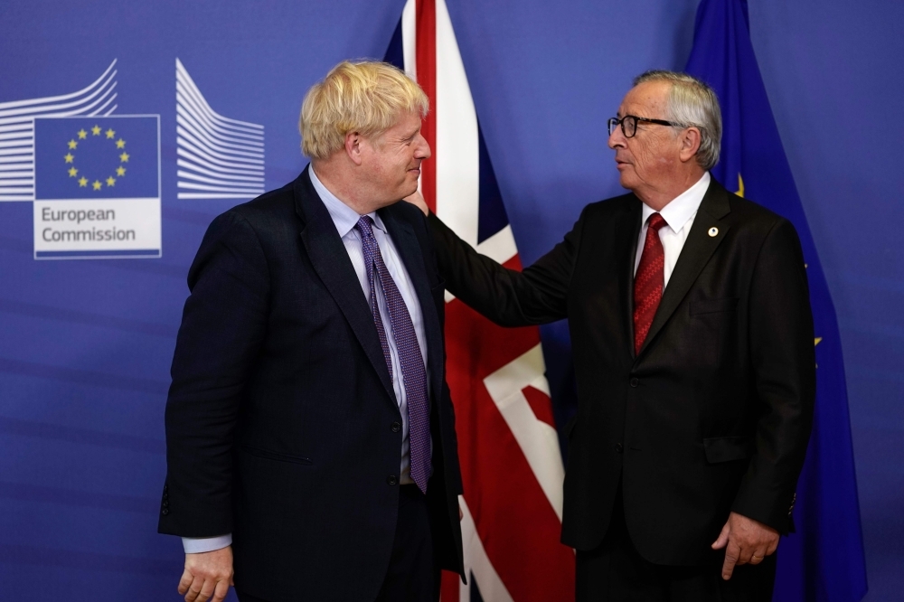 British Prime Minister Boris Johnson (L) looks towards President of the European Commission Jean-Claude Juncker as they address a press conference at a European Union Summit at European Union Headquarters in Brussels on Thursday. — AFP