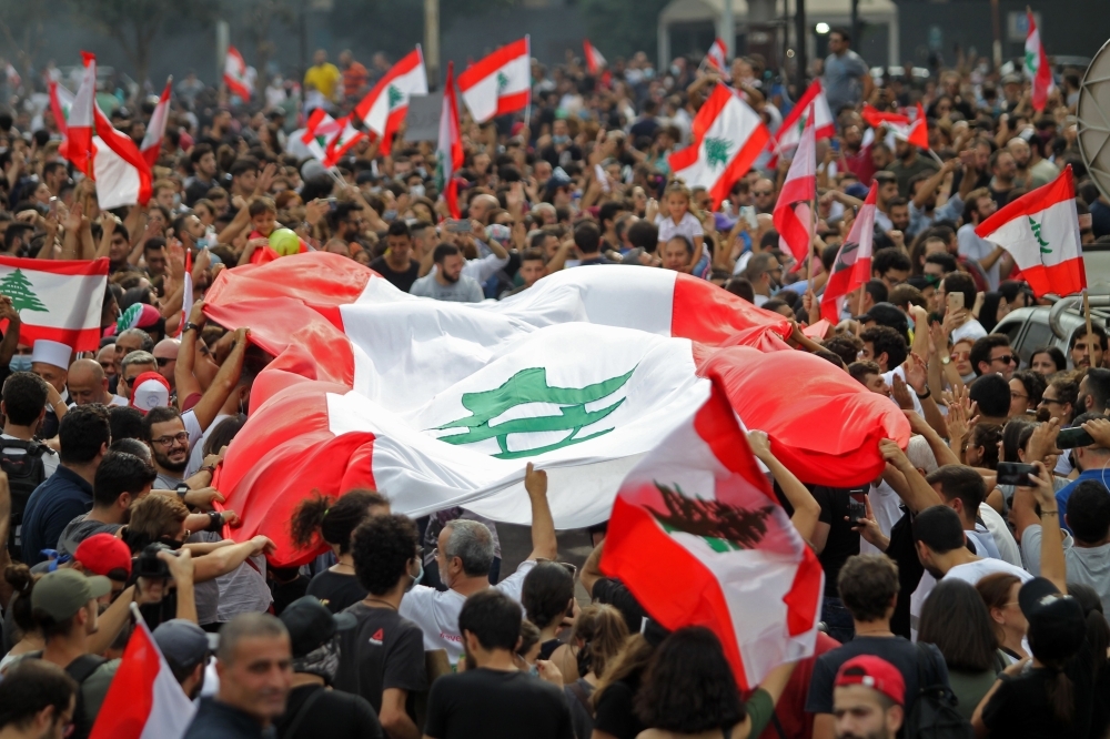 Lebanese demonstrators wave the national flag during a protest against dire economic conditions in downtown Beirut on Friday. — AFP