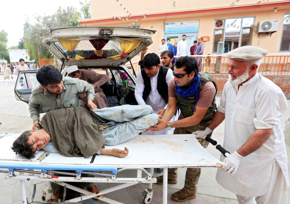 Men carry an injured person to a hospital after a bomb blast at a mosque in Jalalabad in Afghanistan, Friday. — Reuters