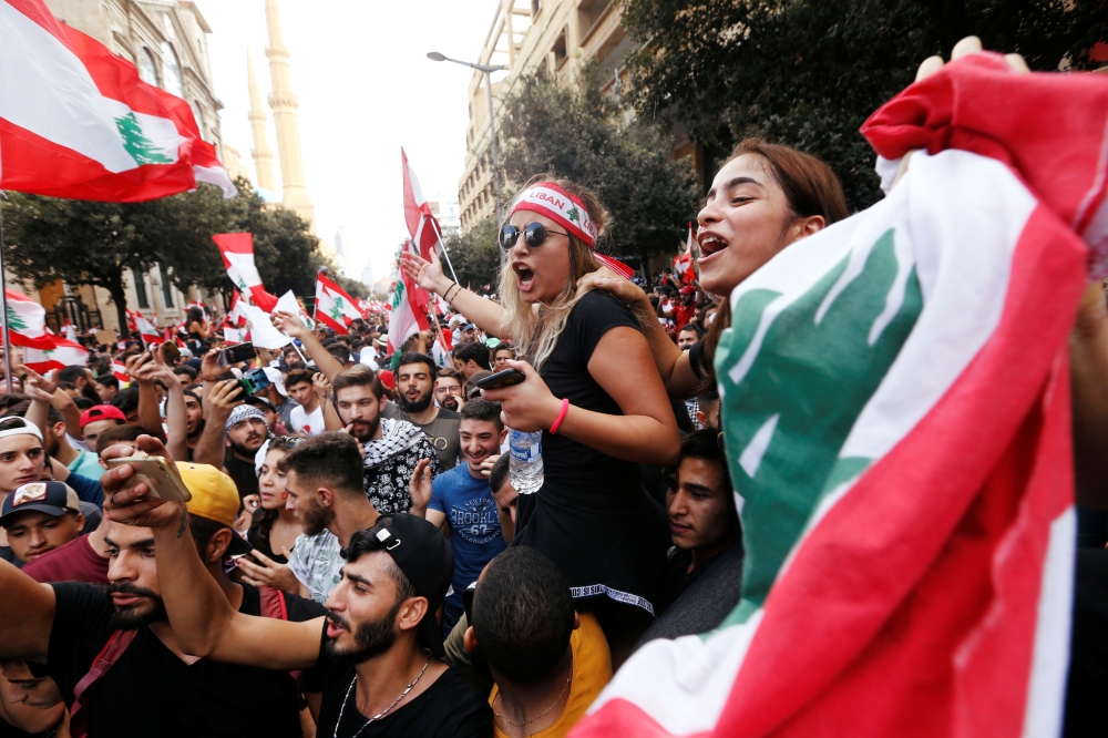 Demonstrators hold national flags during an anti-government protest in downtown Beirut, Sunday. — Reuters