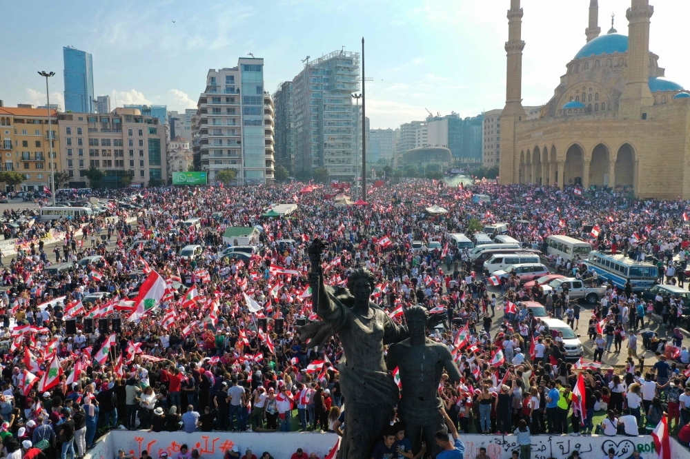 Demonstrators hold national flags during an anti-government protest in downtown Beirut, Sunday. — Reuters