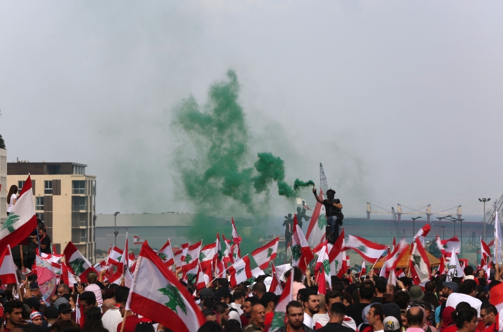 Lebanese protesters wave national flags during a rally in downtown Beirut on Sunday, on the fourth day of demonstrations against tax increases and official corruption. — AFP