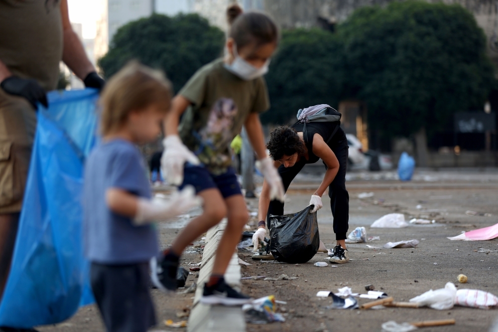 Children help Lebanese members of the civil society clear rubbish on a street in the capital Beirut's downtown district following a night of protests against tax increases and official corruption, on Monday. — AFP
