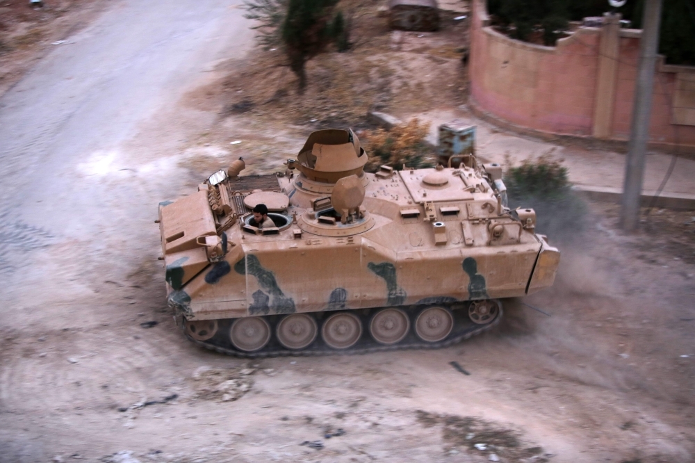 A picture taken on Sunday shows a member of Turkey-backed forces in a Turkish armored personnel carrier in the Syrian border town of Tal Abyad which they seized last week. — AFP