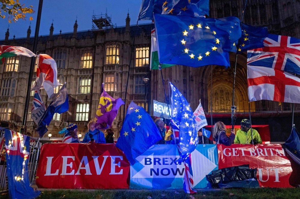 Pro and anti-Brexit protesters wave flags and hold banners as they demonstrate outside of the Houses of Parliament in central London on Monday. — AFP
