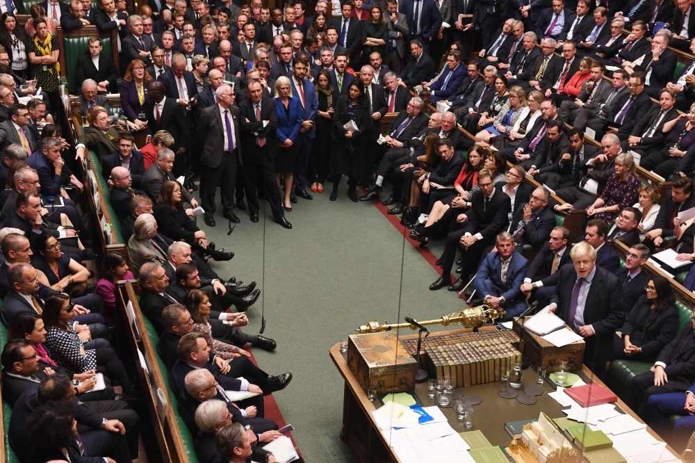 A handout picture released by the UK Parliament shows members of parliament crowding the benches and the aisle listening to Britain's Prime Minister Boris Johnson, right, speak after the results of the vote on the program motion proposing a timetable for the passage of the Brexit Withdrawl Agreement Bill in the House of Commons in London on Tuesday. — AFP