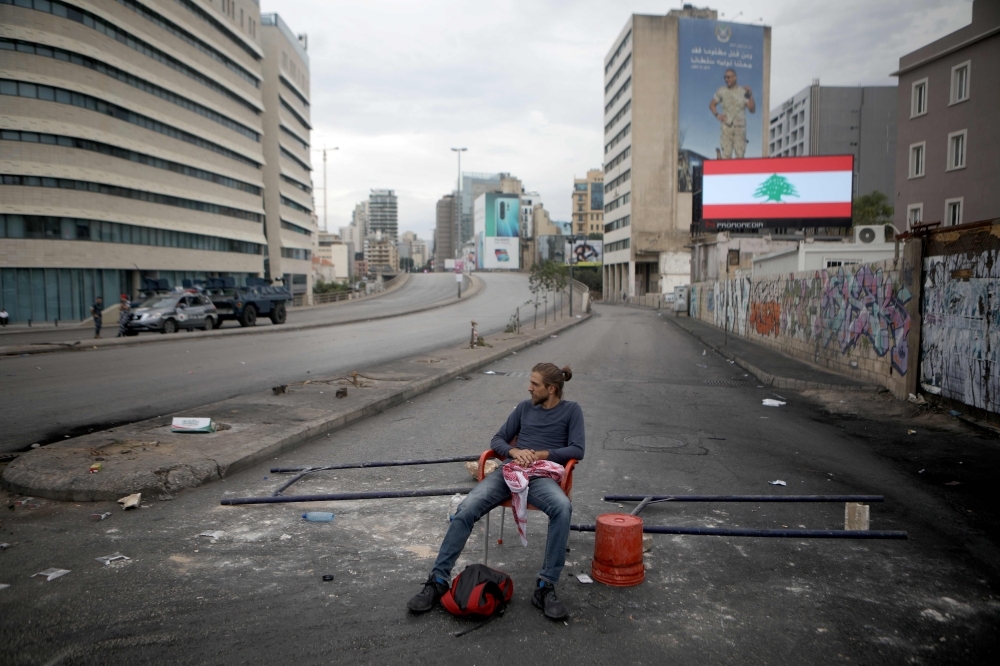 A Lebanese protester sits on a road block on a main avenue leading to the Eastern part of the Lebanese capital Beirut as demonstrations to demand better living conditions and the ouster of a cast of politicians who have monopolized power and influence for decades, continue on Wednesday. — AFP