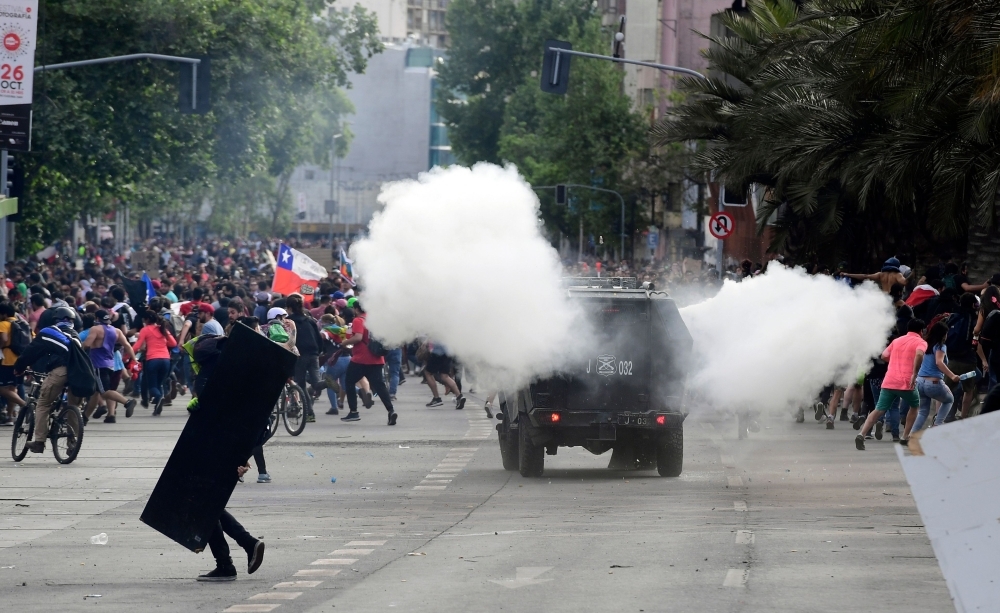 Demonstrators clash with riot police on the fifth straight day of street violence which erupted over a now suspended hike in metro ticket prices, in Santiago, on Tuesday. — AFP