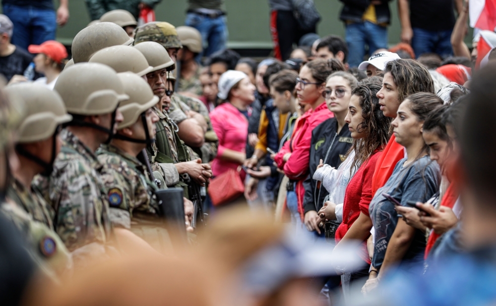 Female protesters stand in a line before Lebanese army soldiers during a demonstration on the seventh day of protest against tax increases and official corruption, in Zouk Mosbeh, north of the capital Beirut, on Wednesday. The almost one-week-old massive street protests in Lebanon, sparked by a tax on messaging services such as WhatsApp, have morphed into a united condemnation of a political system seen as corrupt and beyond repair. — AFP