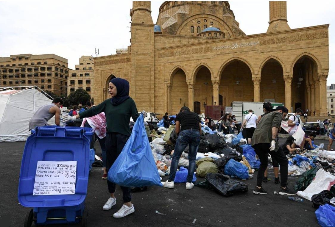 A young woman sorts recycling into a bin in front of the Mohammad Al-Amin Mosque in Beirut, Lebanon on Wednesday. — Reuters